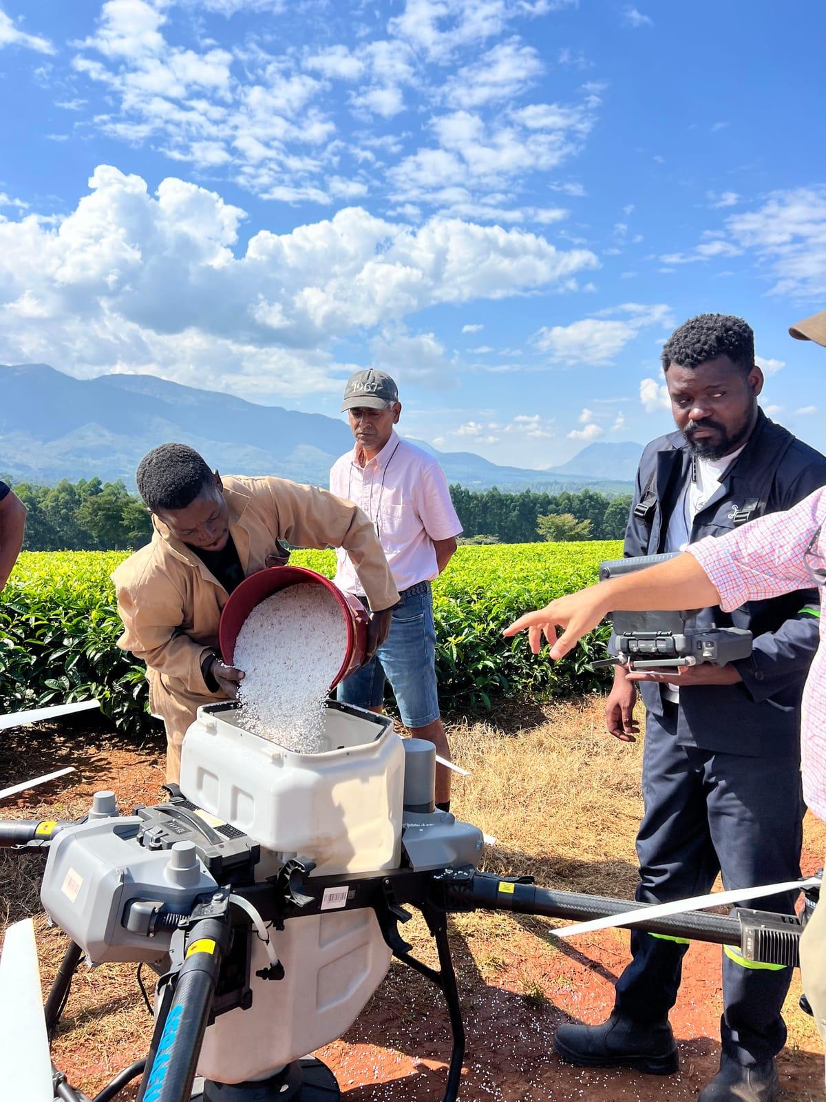 Team member loading granular fertilizer into the drone spreader