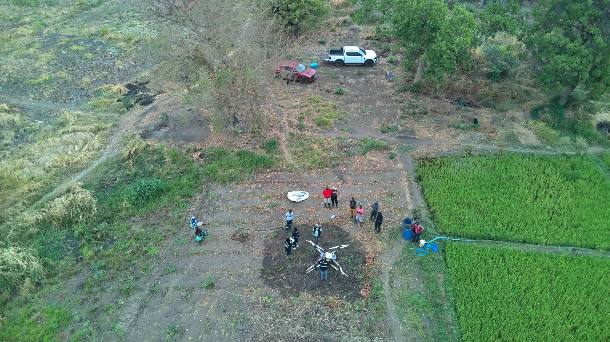 Aerial view of the Serafin team and spray drone beside rice paddies in Salima